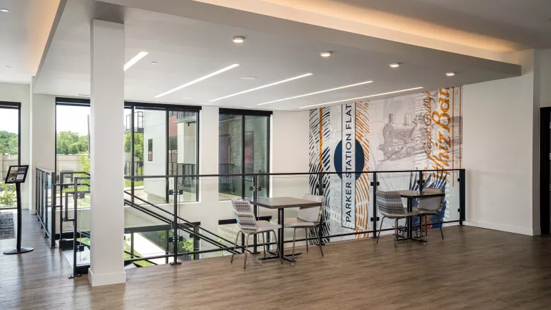 Bright, multi-level modern interior with two seating areas and a large, abstract mural on the back wall.