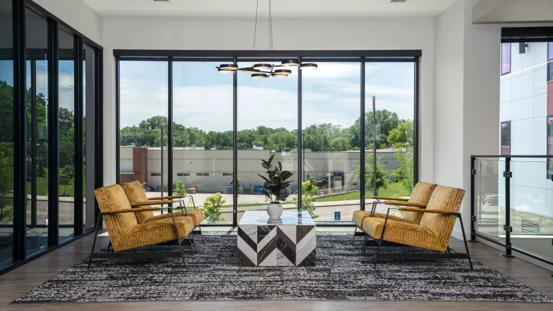 Contemporary lounge with two mustard armchairs, a geometric coffee table, and a wide window view.