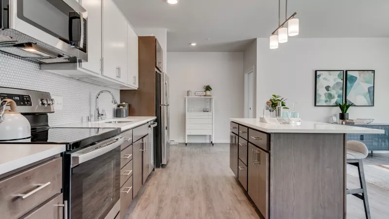 Modern kitchen with white upper, wood lower cabinets, stainless steel appliances, and a large island with a white counter.